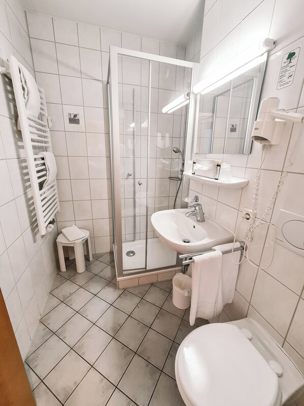 Une salle de bain moderne avec une douche à parois de verre, un lavabo blanc et des toilettes.