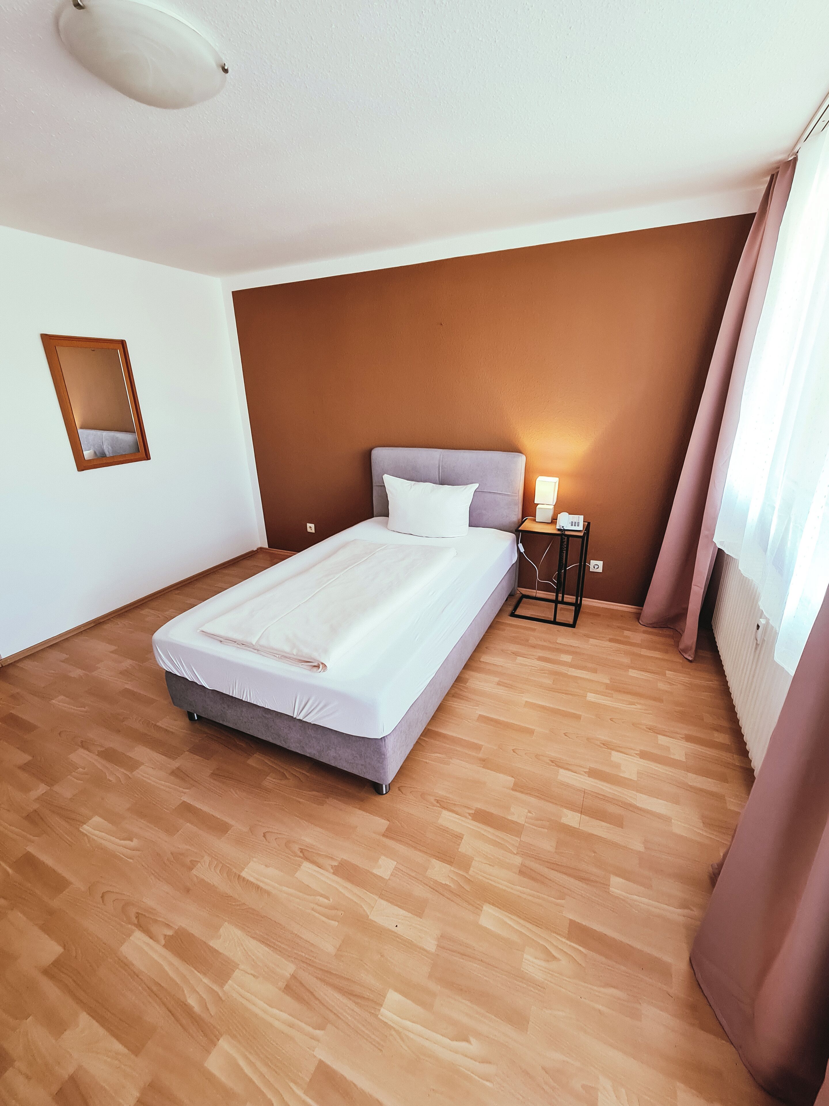 Une chambre à coucher avec un lit, une table de chevet, une lampe et un miroir.