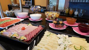 Ein Buffet mit verschiedenen Speisen, darunter Fleisch, Käse und Obst.