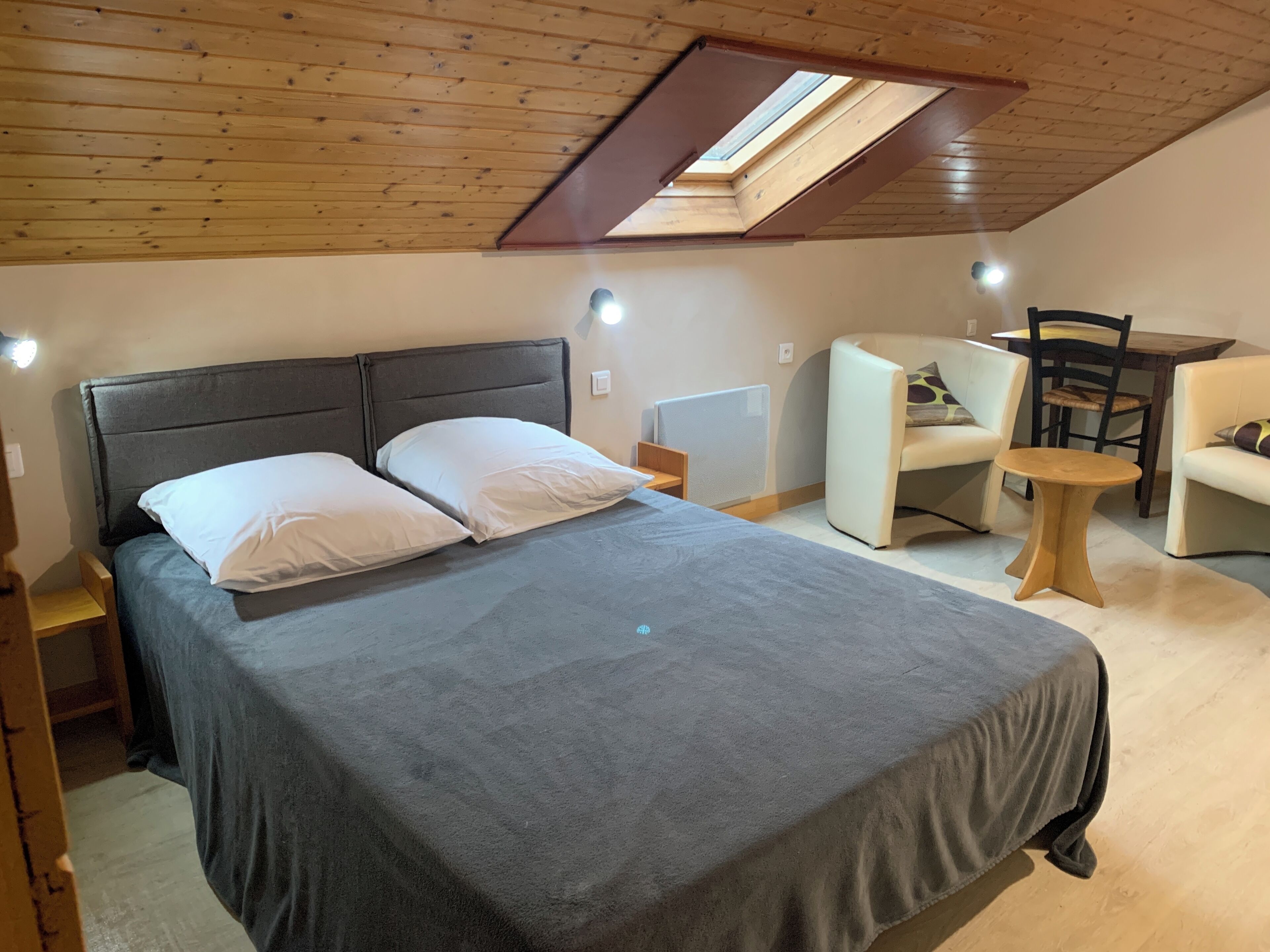 Ein Schlafzimmer mit einem Bett, einem Schreibtisch, einem Stuhl und einem Oberlicht.