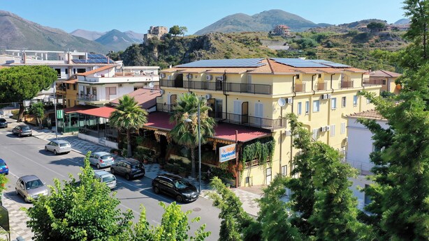 Un hotel de techo rojo, paneles solares y vistas a las montañas.
