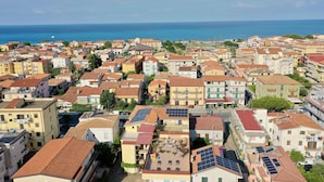 Un pueblo costero con edificios de tejados de teja y paneles solares en los tejados, con vista al mar.