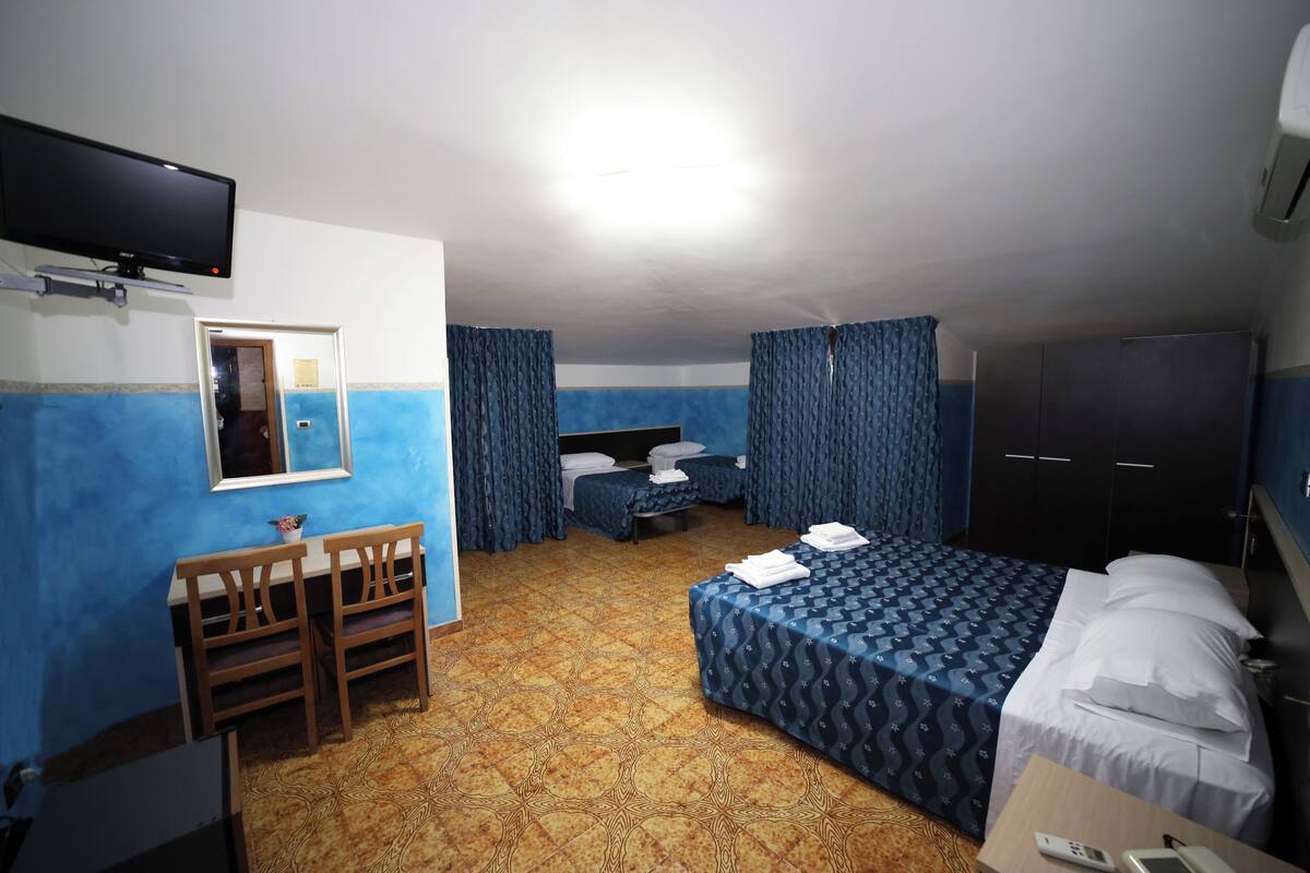 Hotellihuone, jossa on sänky, työpöytä, tuoli, televisio ja vaatekaappi.