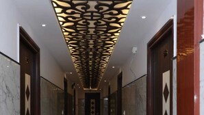 Ein Flur mit Marmorböden und Türen, mit einer dekorativen Decke mit geometrischem Muster.