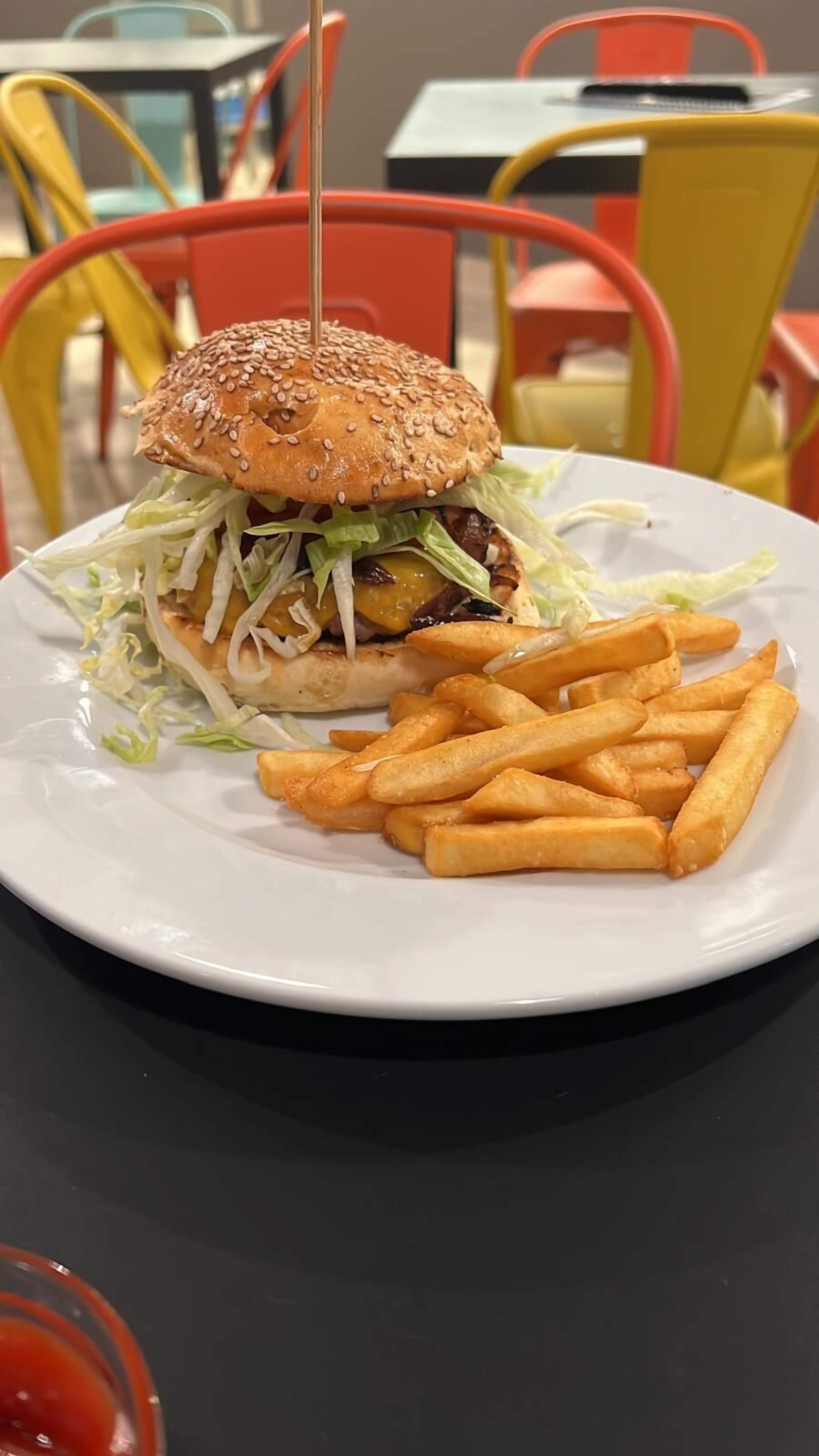 Un plato con una hamburguesa y papas fritas sobre una mesa.