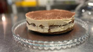 A slice of tiramisu on a clear glass plate.