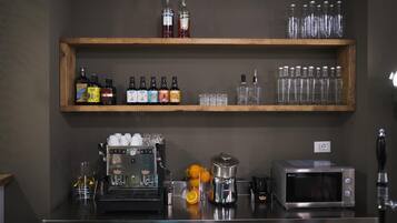 En bardisk med hyllor fulla av spritflaskor, glas, en kaffemaskin, en vattenkokare och en mikrovågsugn.