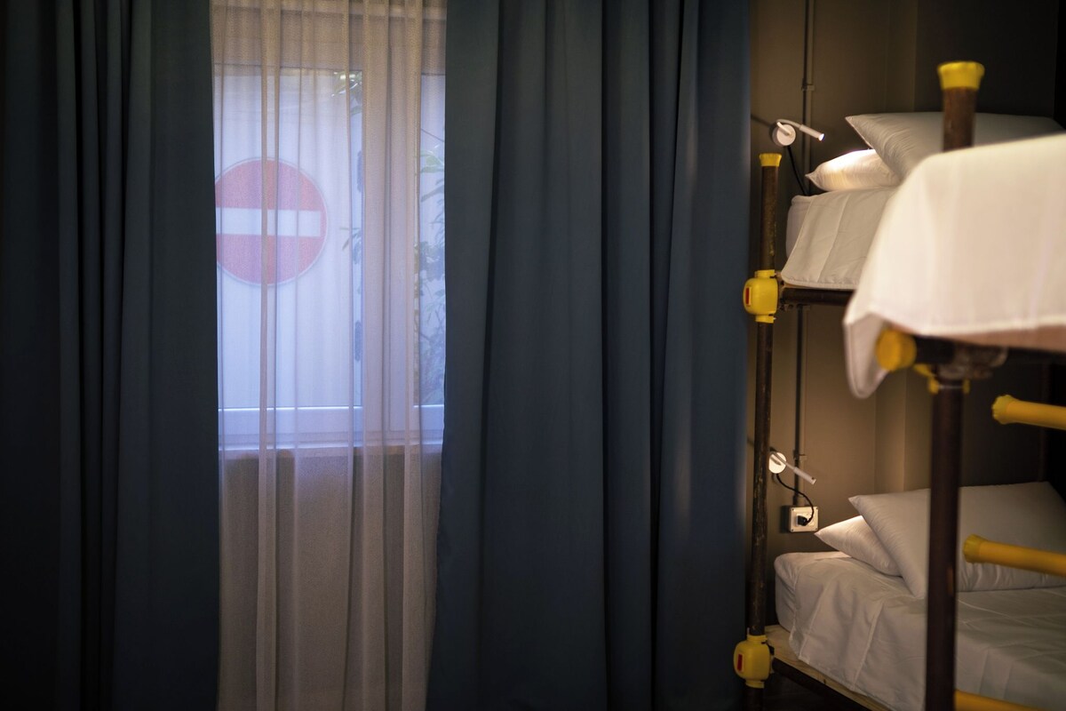 A bunk bed with white bedding and a window with a 'no entry' sign.