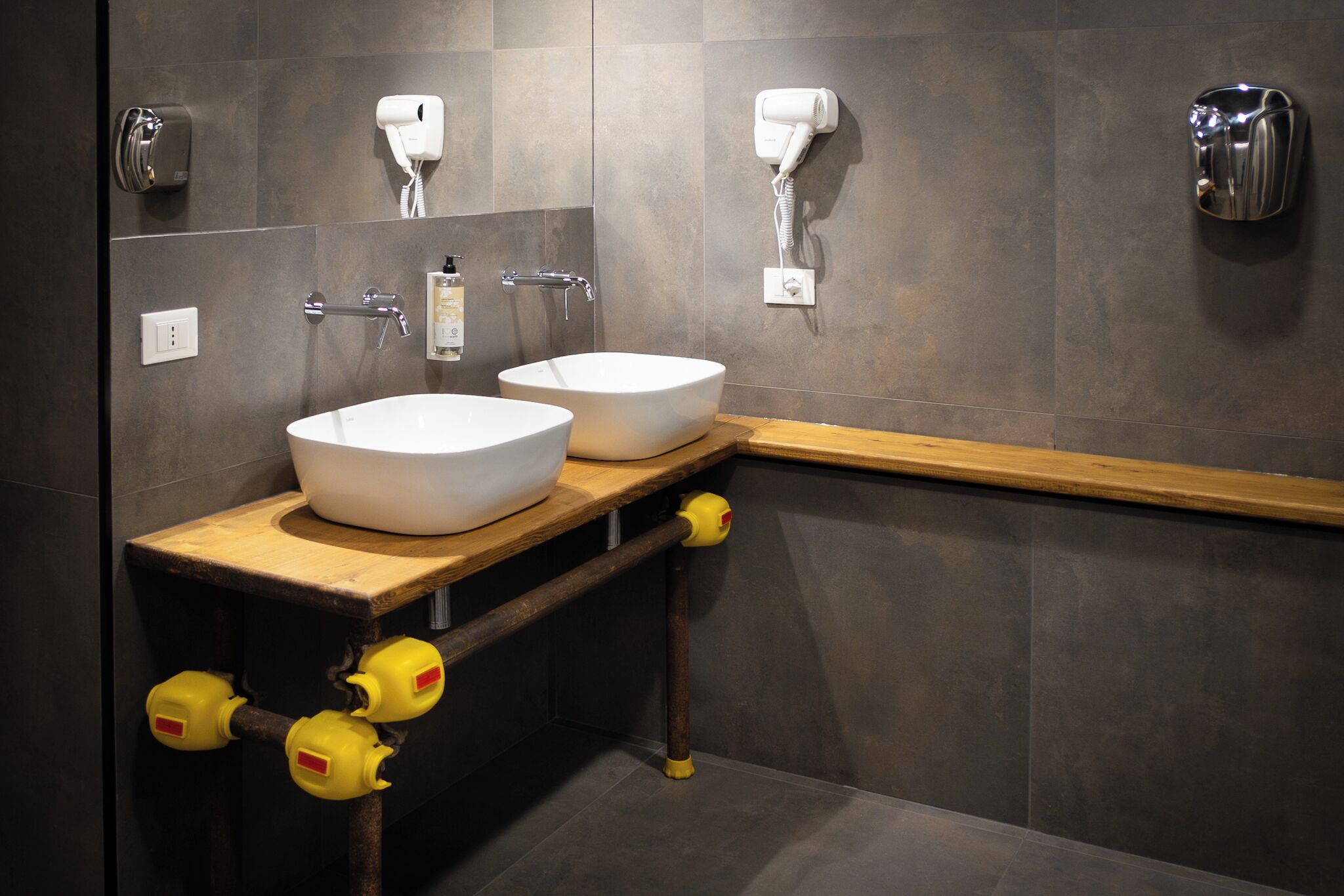 Une salle de bain avec deux lavabos, un distributeur de serviettes, un sèche-cheveux et un distributeur de savon.