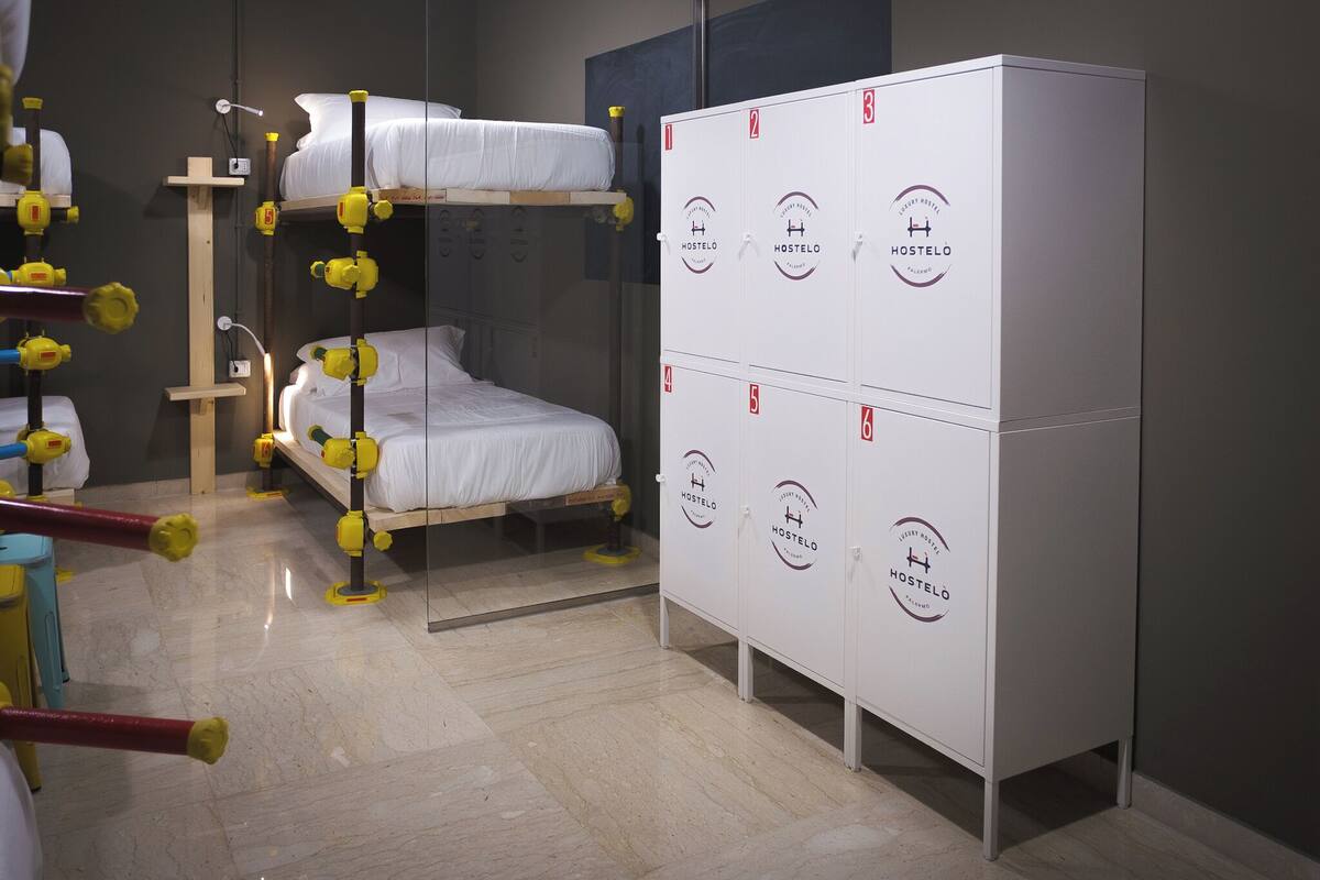 A hostel room with bunk beds, a wardrobe, and a water dispenser.