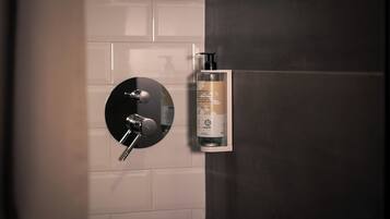 Een badkamer met een moderne kraan en een fles Dove bodylotion aan de muur.