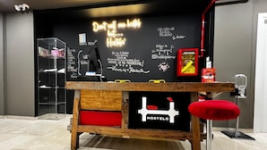 A hostel with a wooden table, a neon sign, and a chalkboard wall with travel-related writings. - Hostelò Luxury Hostel (Palermo)
