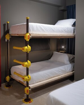 A bunk bed with a ladder, a small table, and a nightstand. - Hostelò Luxury Hostel (Palermo)
