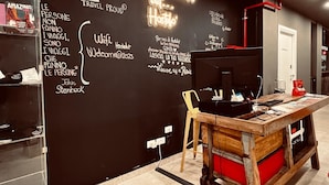 A cozy room with a blackboard wall featuring travel-related writings and a neon sign. - Hostelò Luxury Hostel (Palermo)