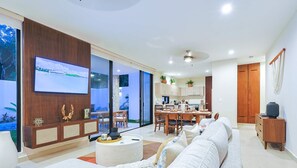 Relax in this spacious living room with a large flat-screen TV, comfortable seating area, and dining space.