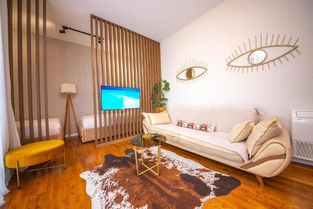 A modern living room with a sofa, a glass coffee table, a wooden partition, and a TV on the wall.