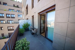 A balcony with a table and chairs, a potted plant, and a view of the city. - Green Terrace Apartments Tirana (Tirana)