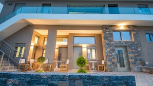 A modern building with a balcony, outdoor seating area, and a stone facade. - Mylos 2 apt, Apartment (Agios Nikolaos)