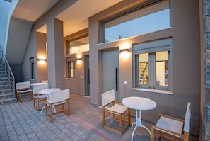Un espace extérieur moderne aménagé avec des tables et des chaises, un escalier et une grande fenêtre.