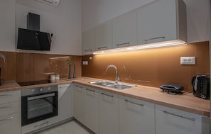 A modern kitchen with a built-in oven, a sink, and a range hood.