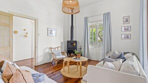 A cozy living room with a fireplace, wooden flooring, and a comfortable seating area.
