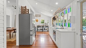 Una cocina moderna con una isla central, un comedor con mesa de madera y vistas al exterior a través de amplias ventanas.