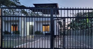 A gated entrance to a building with a covered upper level and a visible door. - The Green-Village Villa (Entebbe)