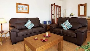 Uma sala de estar com dois sofás de couro marrom, uma mesa de centro de madeira e um quadro na parede.