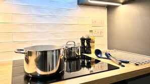 Une cuisine moderne avec une casserole en acier inoxydable, une machine à café et une bouteille d’huile d’olive posées sur le plan de travail.