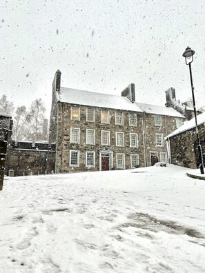 Ein Gebäude aus Stein mit vielen Fenstern und einem mit Schnee bedeckten Dach.