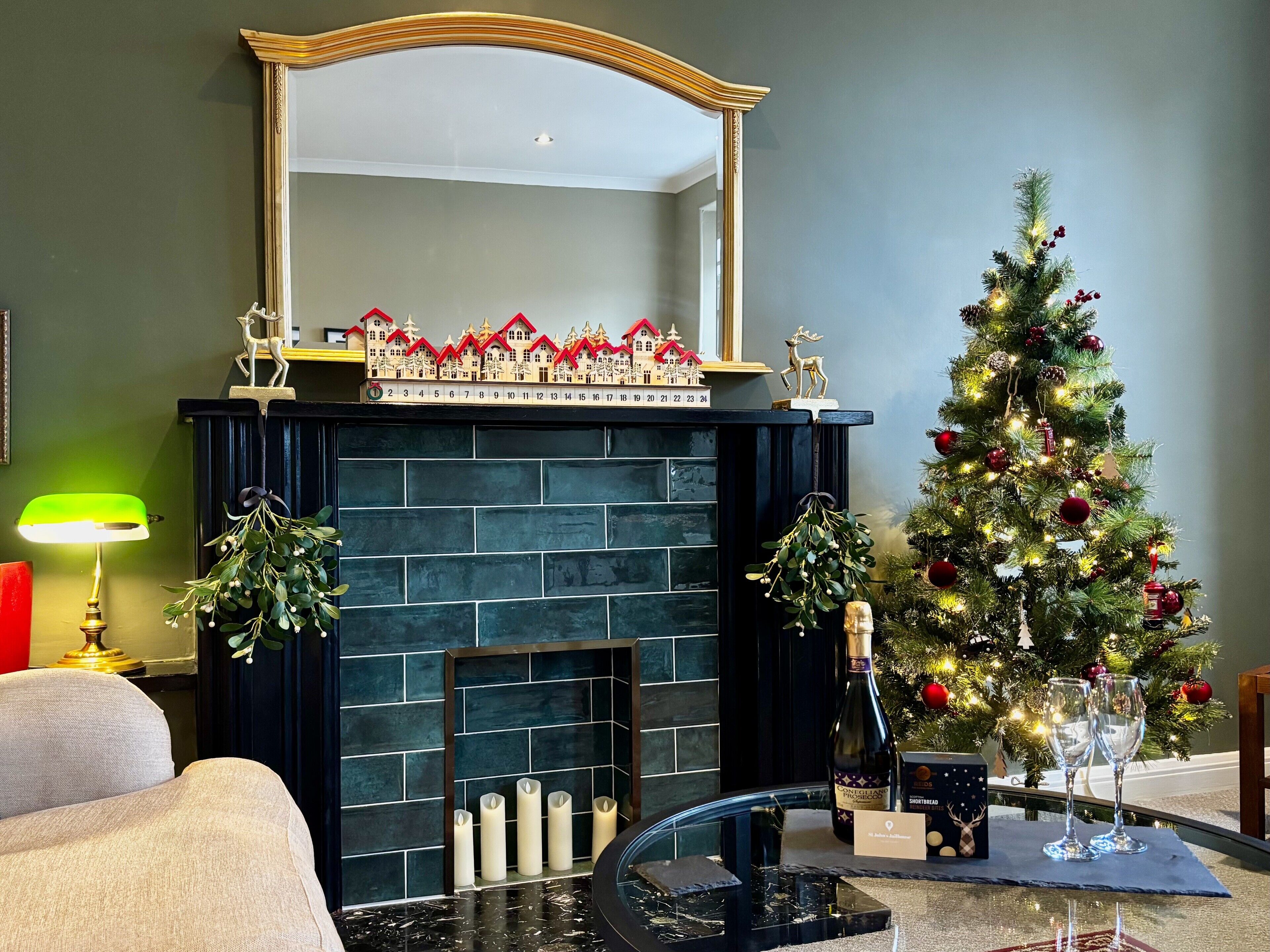 Una sala de estar con chimenea, un árbol de Navidad y una mesa con vasos y una botella.