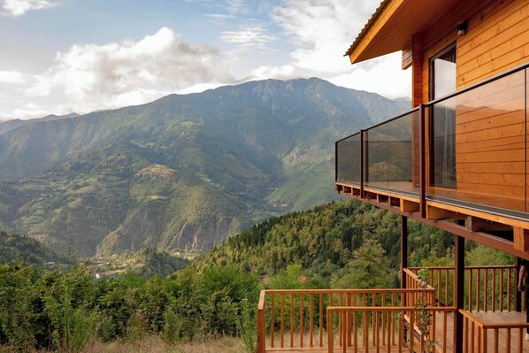 A wooden cabin with a balcony overlooking a mountainous landscape.