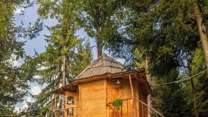 A wooden treehouse with a balcony and stairs, surrounded by dense forest. - Hill Inn (Keda)