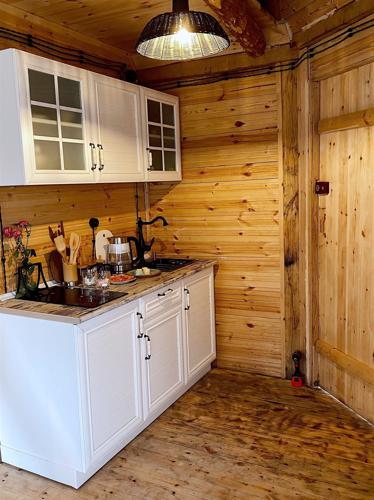 A wooden interior with white cabinetry, a kitchen island, and a hanging light fixture.