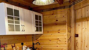 A wooden interior with white cabinetry, a kitchen island, and a hanging light fixture.