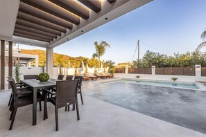 A modern outdoor pool area with a dining setup and lounge chairs.