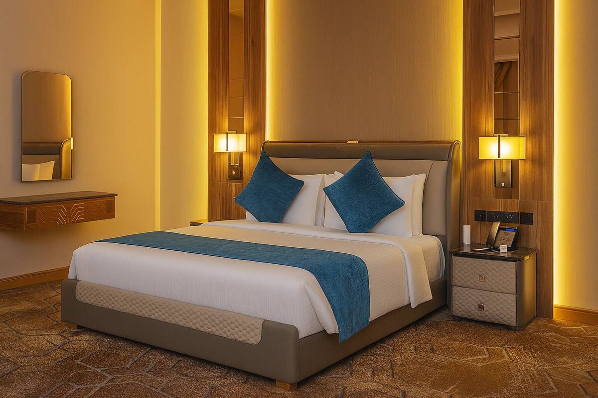 Une chambre d’hôtel avec un grand lit, deux tables de chevet, une commode, un miroir et une étagère fixée au mur.