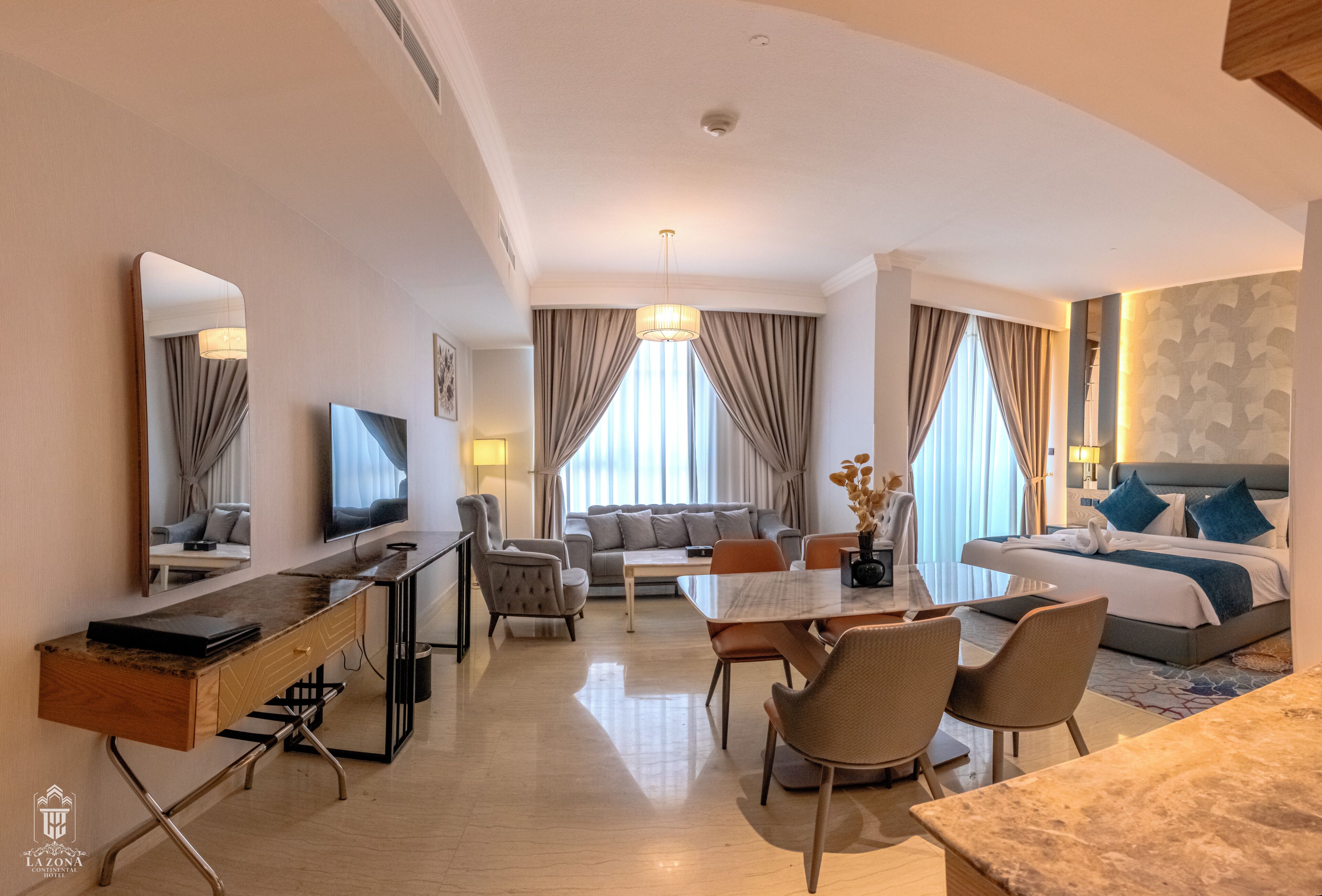 Una habitación de hotel con comedor, sofá, cama y televisión.