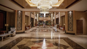 A spacious lobby with a large chandelier, marble flooring, and symmetrical wall designs. - La Zona Continental Hotel (Dubai)
