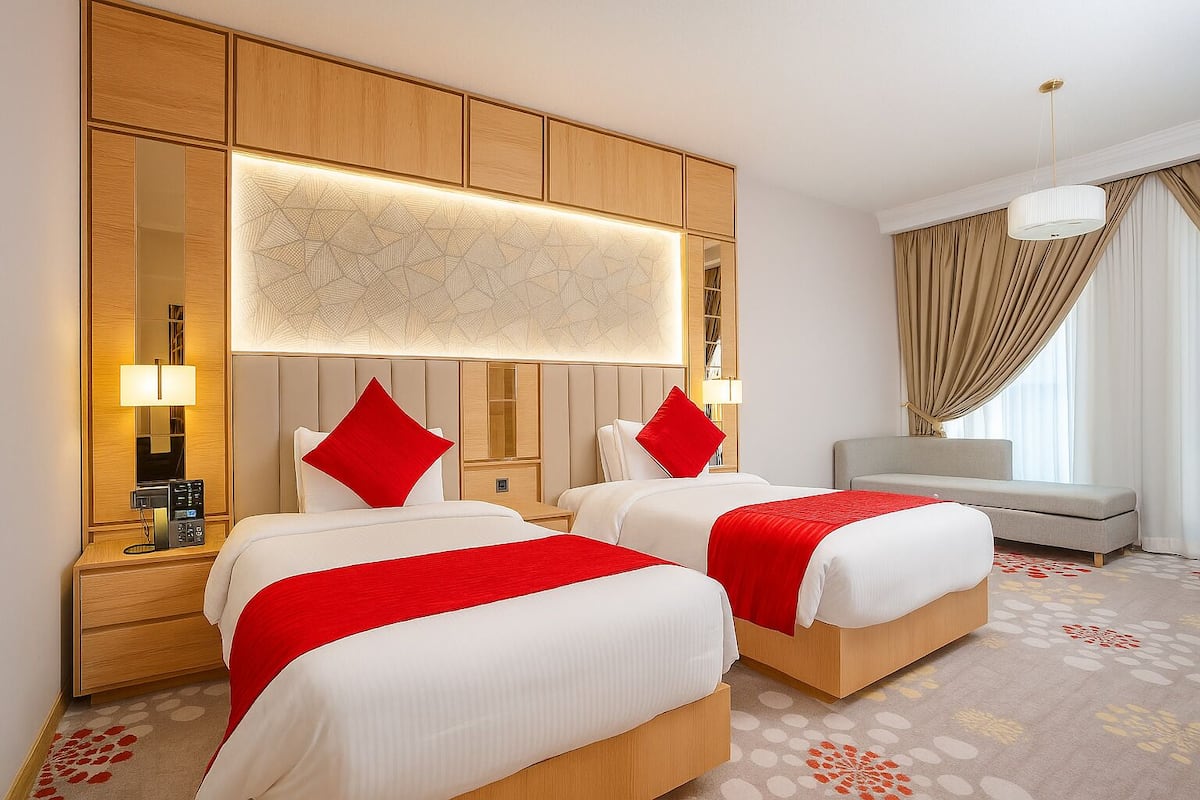 Une chambre d’hôtel avec deux lits, un canapé, un grand miroir et un lustre.