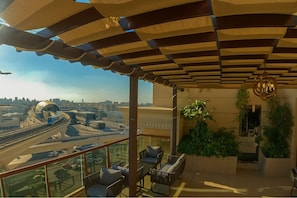 A balcony with a view of a highway and cityscape, furnished with wicker chairs and a table. - La Zona Continental Hotel (Dubai)
