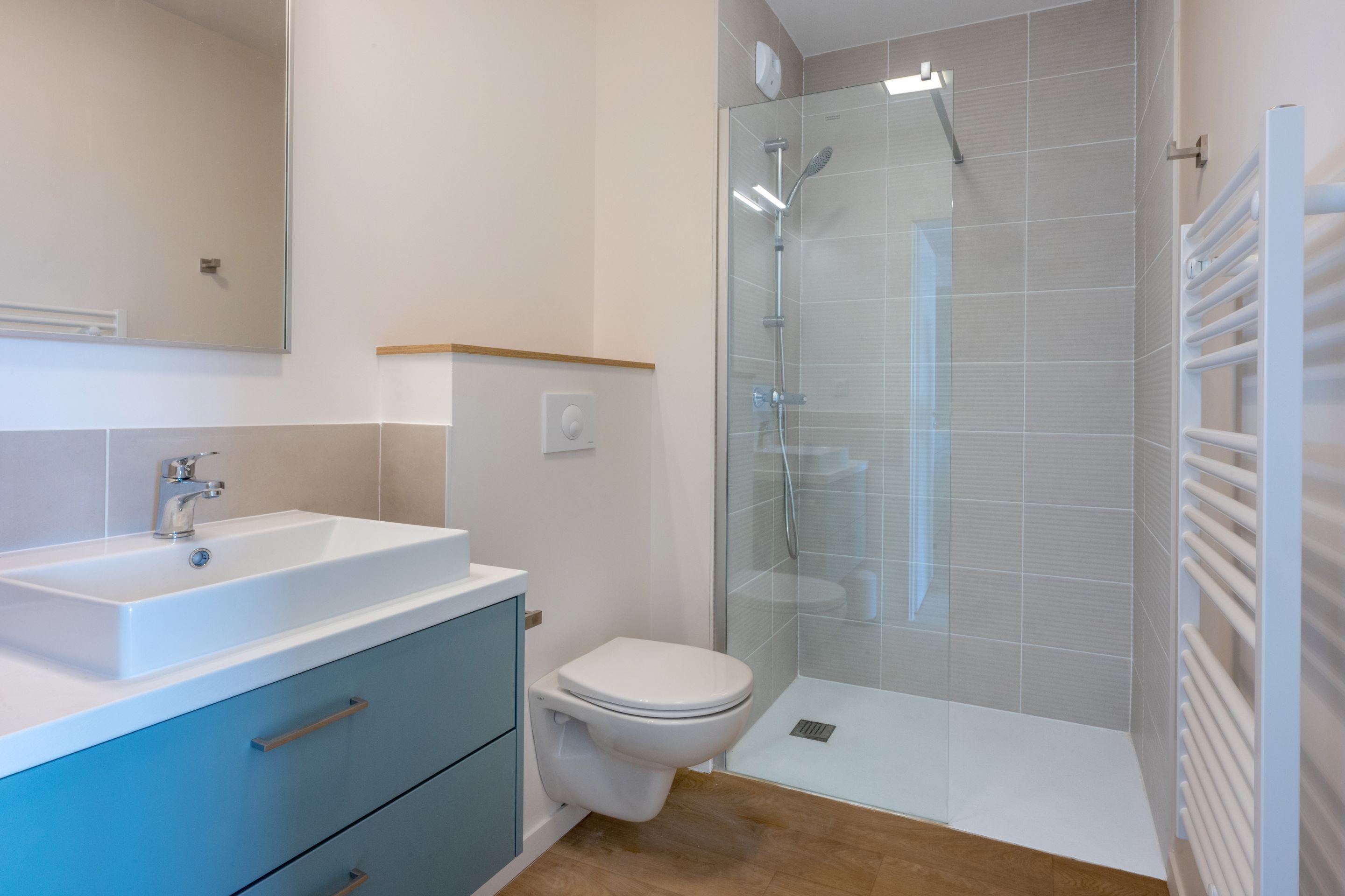 A modern bathroom with a glass-enclosed shower, a white sink, and a toilet.