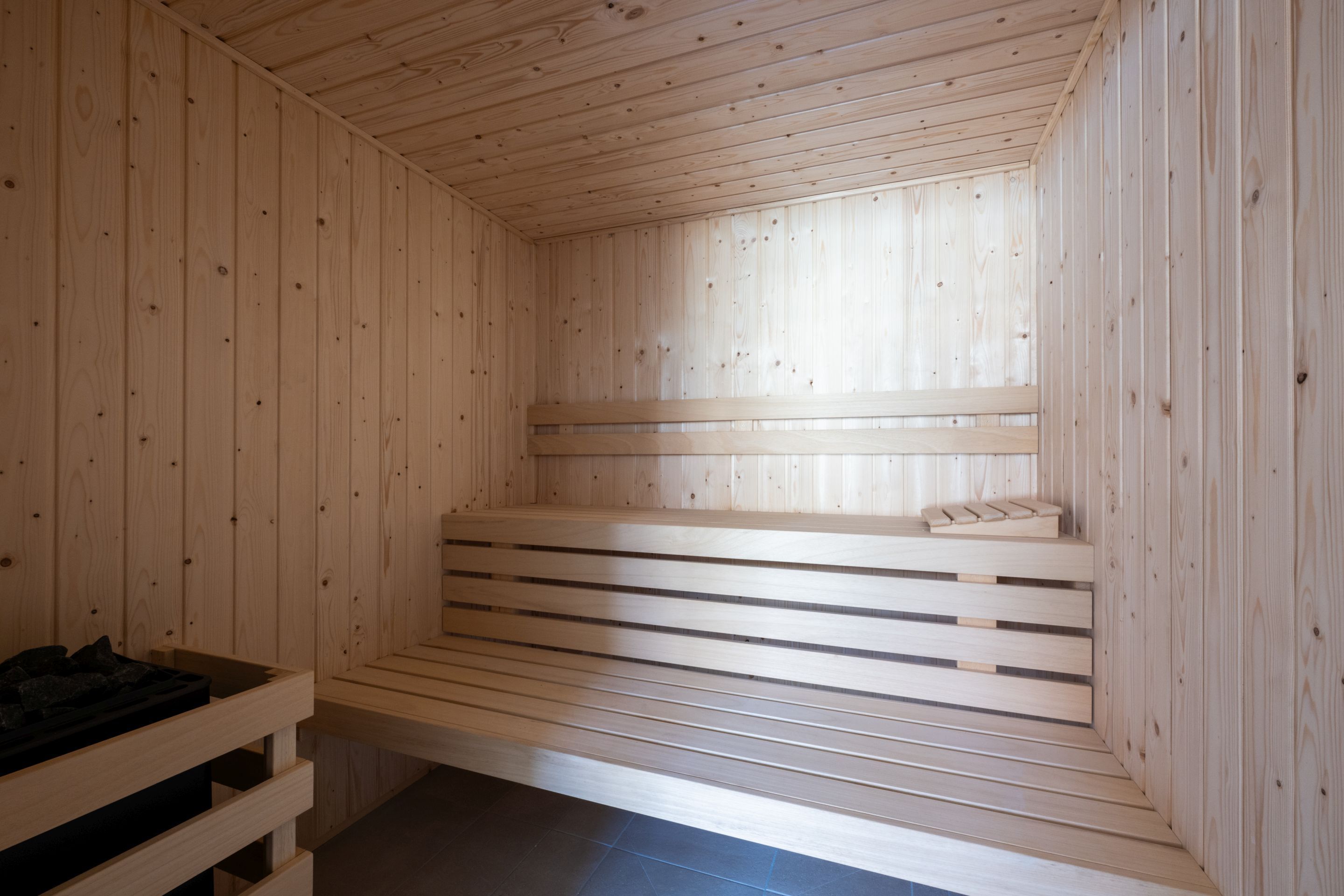 Eine Sauna mit Holzbänken und einer Liege mit einer schwarzen Matte.
