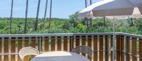 An outdoor patio with a round table and two chairs, an umbrella, and a wooden fence.
