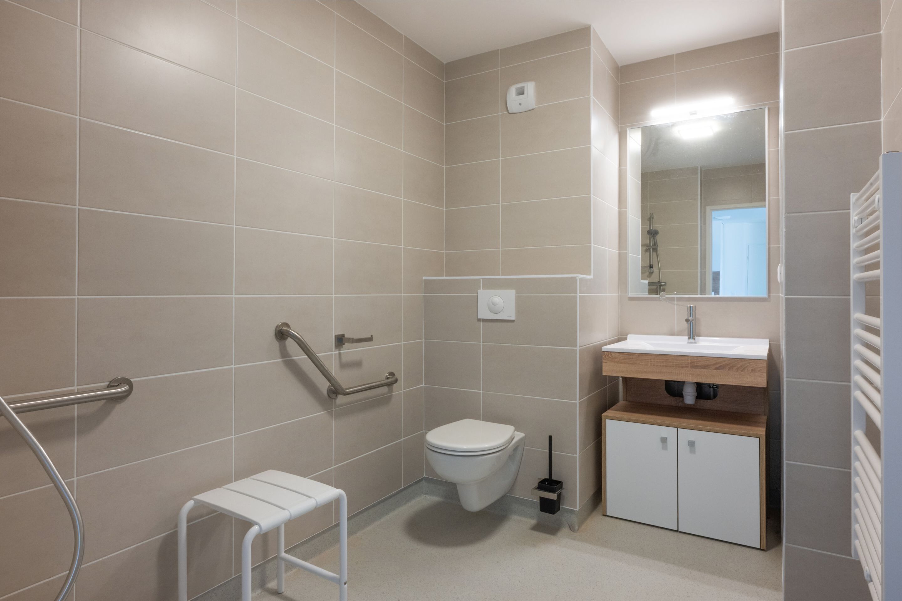 A bathroom with a toilet, sink, mirror, and a small white shelf.