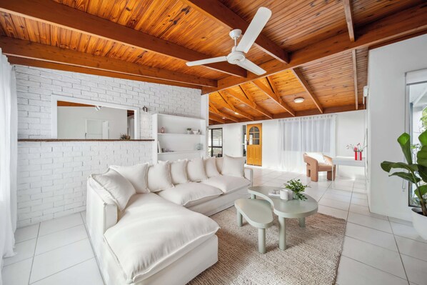 Un salon moderne avec un canapé d’angle, une table basse ronde et un ventilateur de plafond.