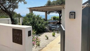 A gated entrance with a pergola and outdoor seating area, overlooking a coastal view. - Domus Aura villa in Sardinia with sea view and pool (Tertenia)