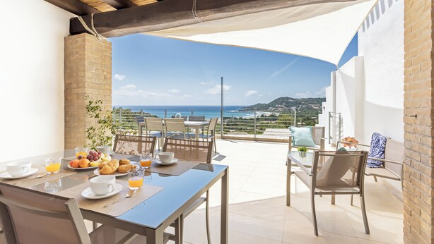 A breakfast setup with a table, chairs, and a view of the sea. - Domus Aura villa in Sardinia with sea view and pool (Tertenia)