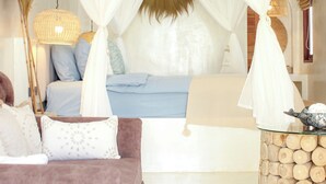 Egy hálószoba baldachinos ággyal, mennyezeti ventilátorral és egy éjjeli asztallal, melyen egy lámpa található.