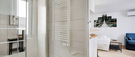 Un bagno moderno con box doccia in vetro, porta asciugamani bianco e termosifone bianco.